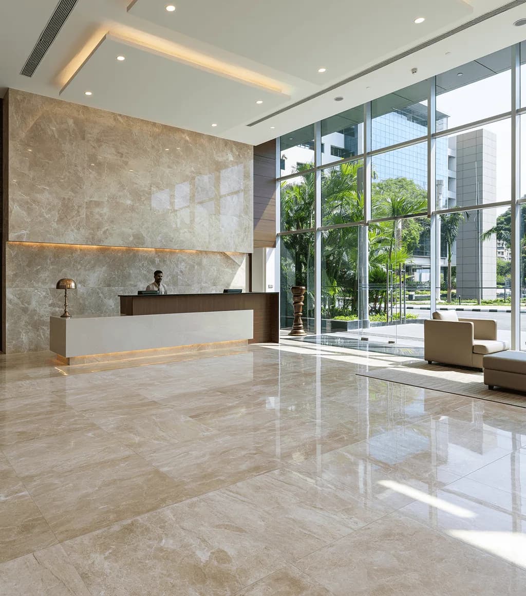 Office lobby reception in beige-cream marble-look large-format floor and wall tile, behind a glass facade