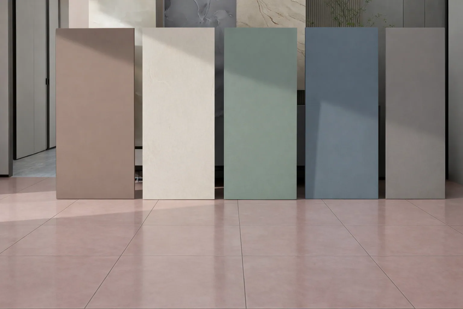 Five plain-colour large-format slabs in clay, cream, sage, denim and grey, leaning against a wall above a pink tiled floor