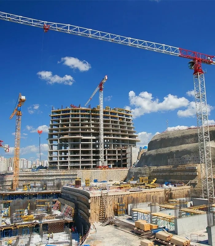 A high-rise tower under construction for AR Construction in the Andaman and Nicobar Islands, tower cranes overhead against a blue sky
