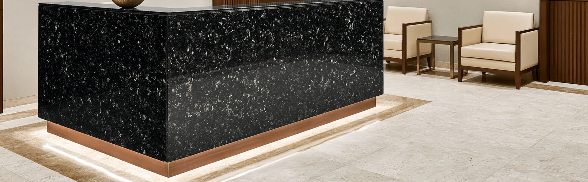 Black galaxy granite reception desk with a bronze base trim