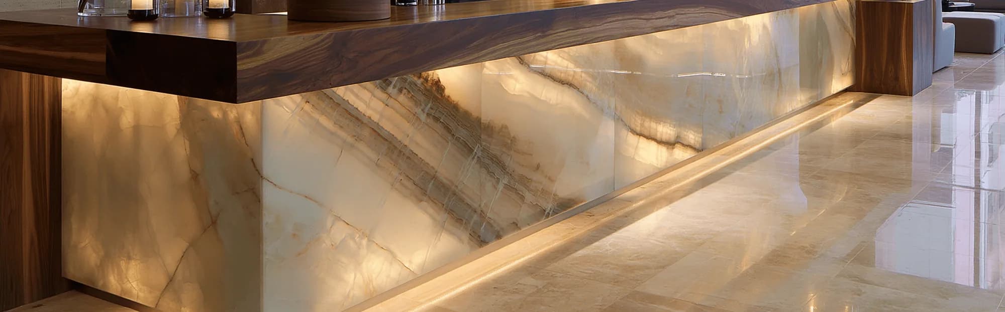 Illuminated onyx-marble bar front with dramatic amber veining, beneath a timber countertop