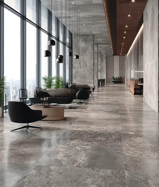 Corporate lounge in grey stone-look floor tile, with floor-to-ceiling glazing and black lounge chairs
