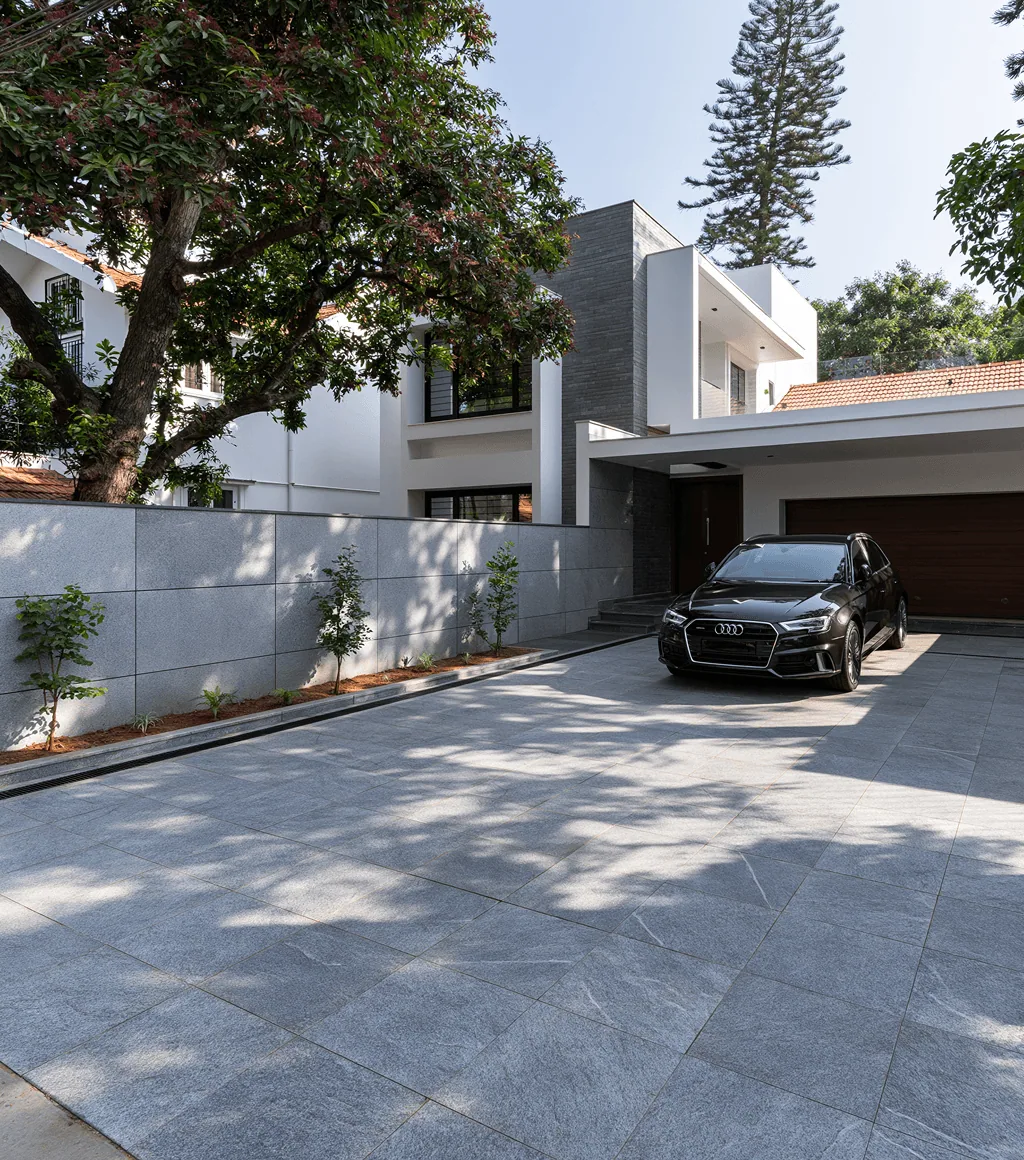 Driveway and boundary wall clad in grey granite, with a car parked under a tree