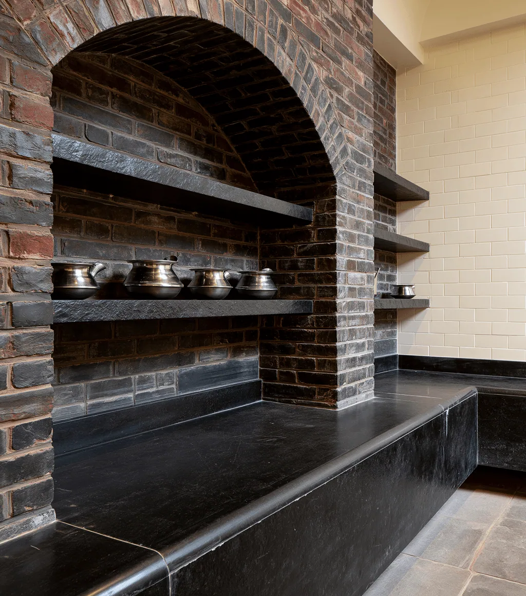 Traditional brick-arched kitchen niche with black stone shelving and a black Kadappa-stone counter