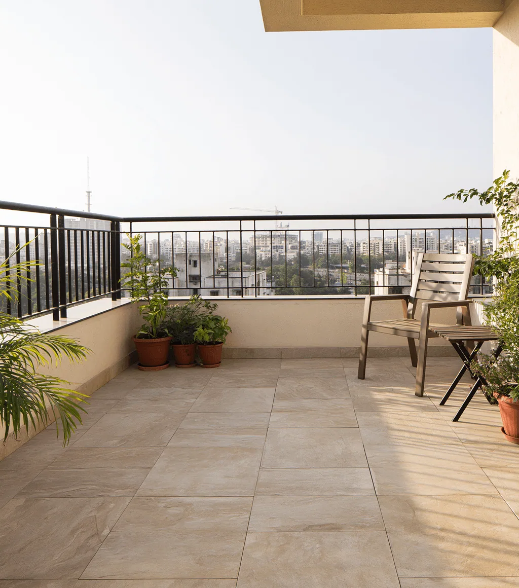 High-rise balcony floored in beige Kota-look large-format tile, with a city skyline view