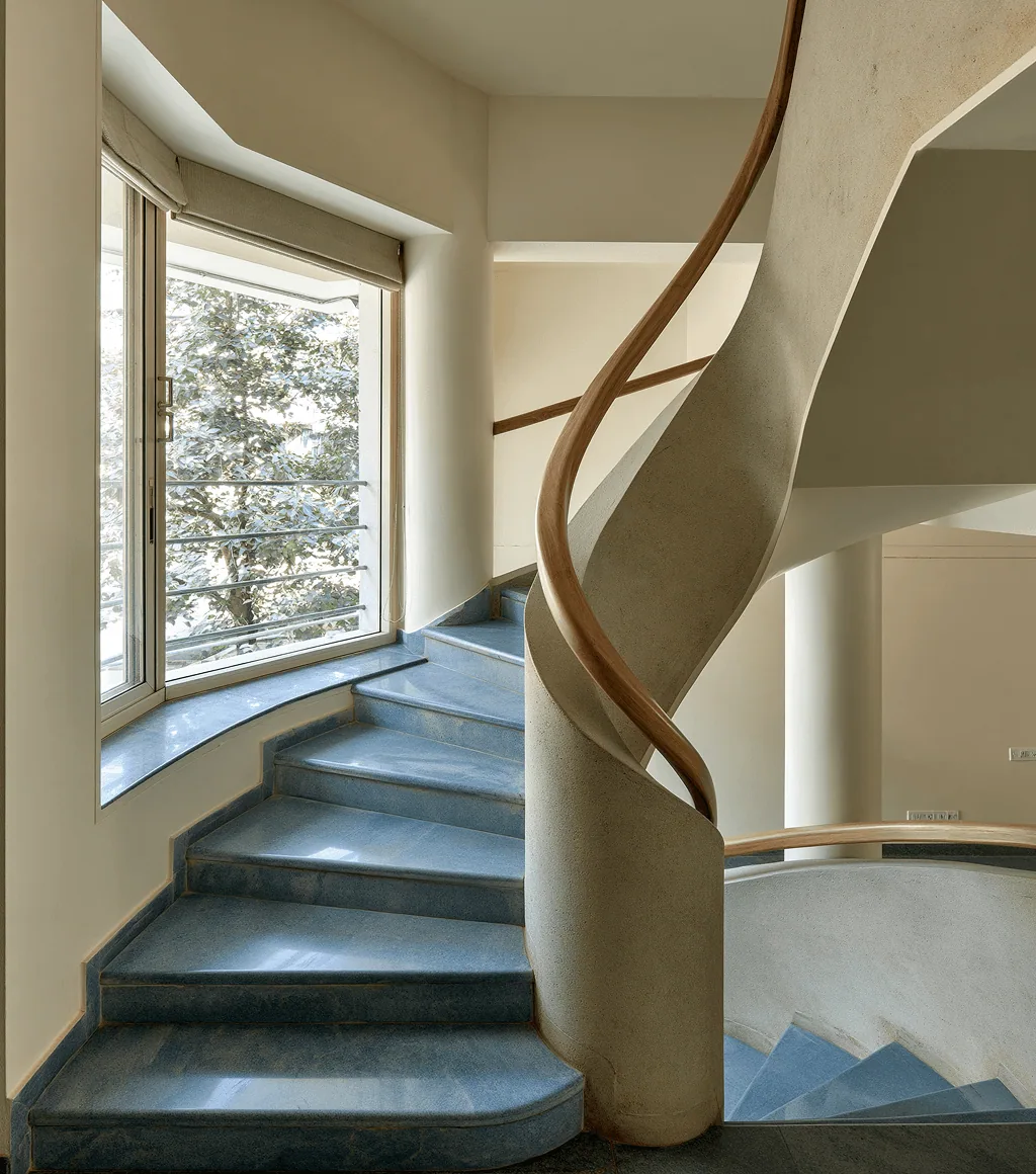 Curved staircase with blue-grey honed Kota-stone treads and a timber handrail