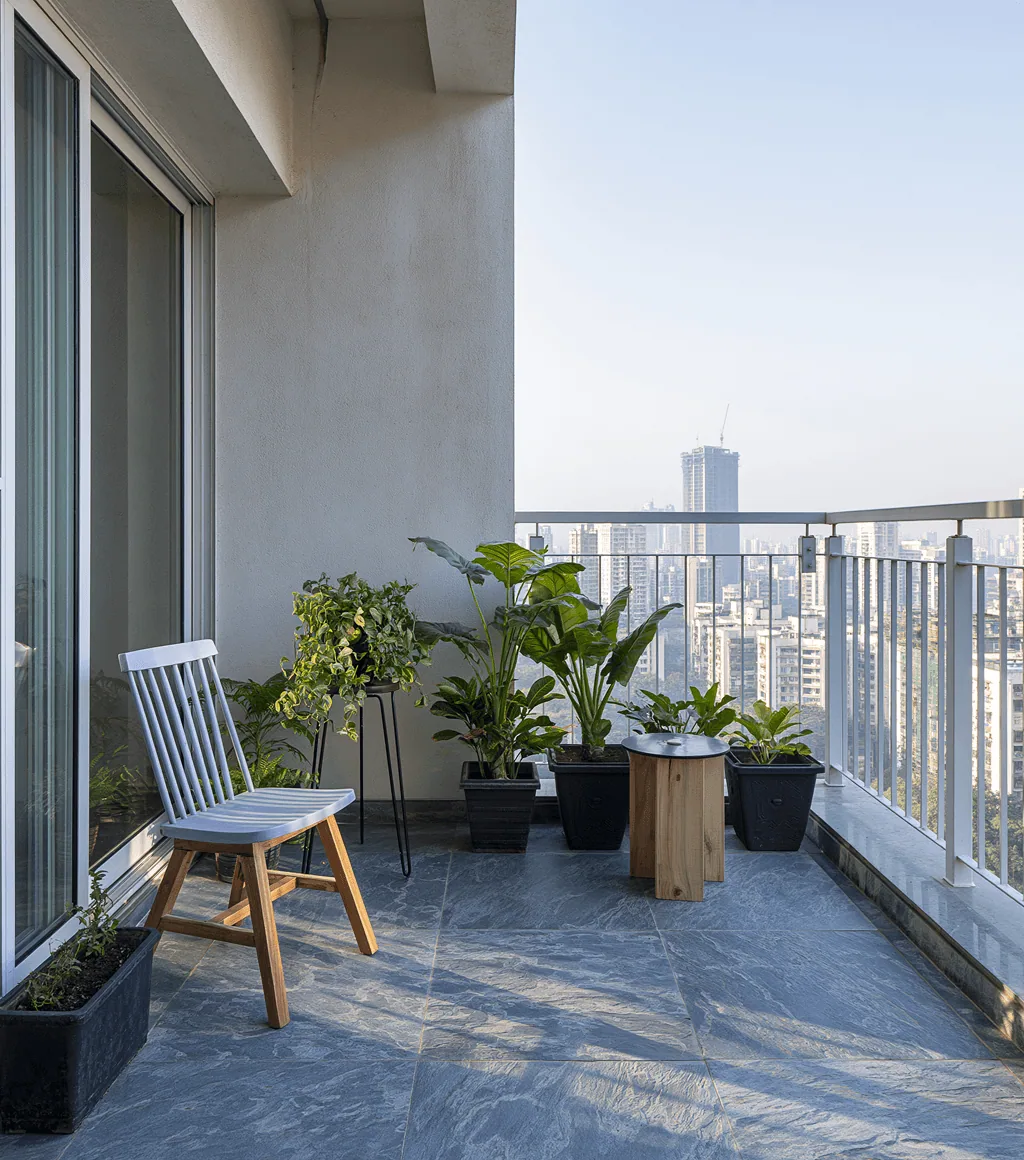 Balcony floored in blue-grey honed Kota stone, with potted plants and a city skyline view
