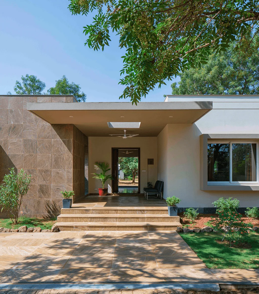 House entrance with a beige stone-clad wall, matching honed Kota-look steps and driveway