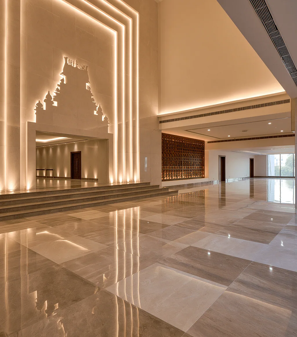 Hotel or banquet lobby in warm taupe polished marble-look floor tile, with a temple-motif backlit wall niche