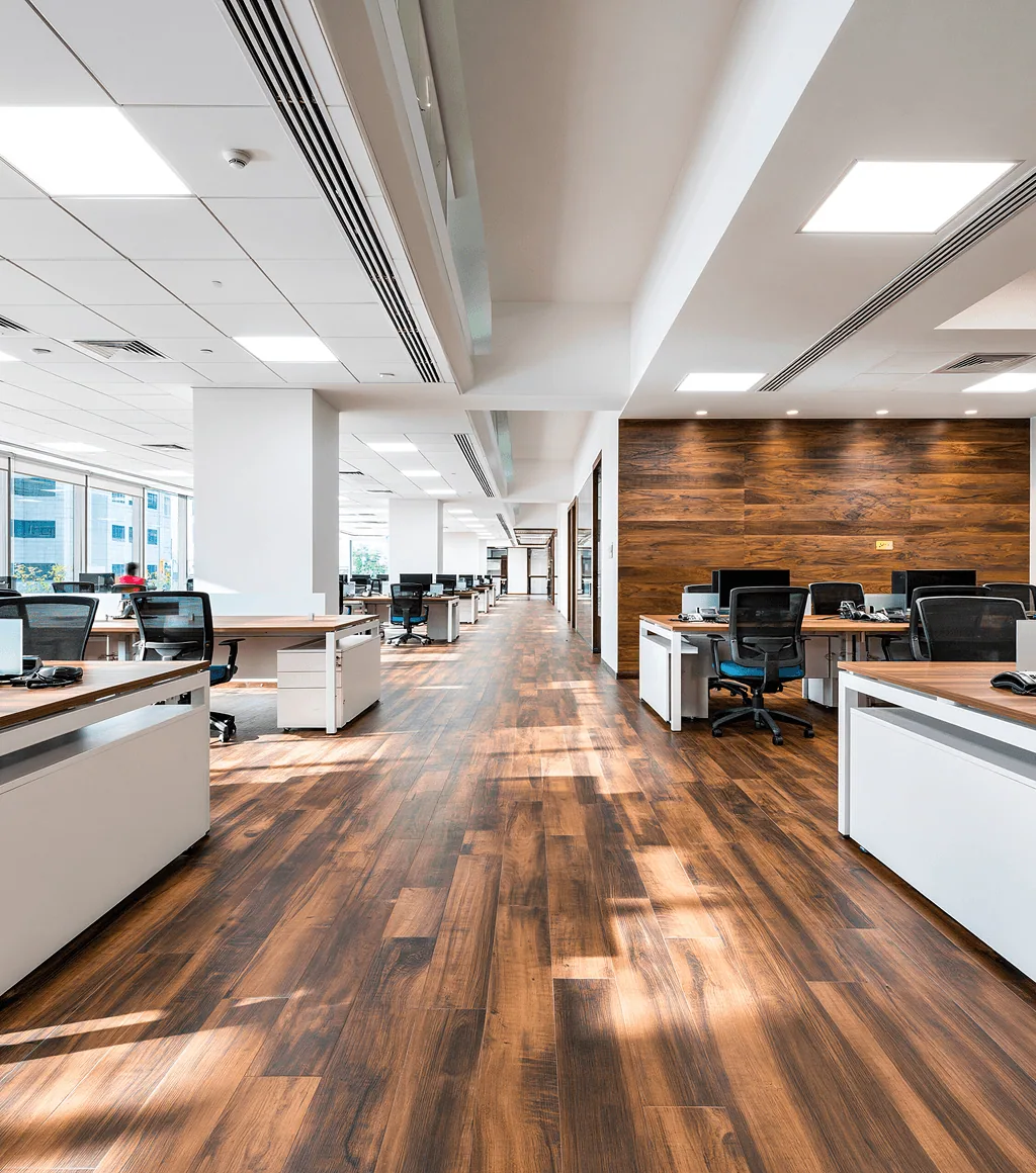 Open-plan office with dark walnut wood-look plank floor tile and rows of workstations