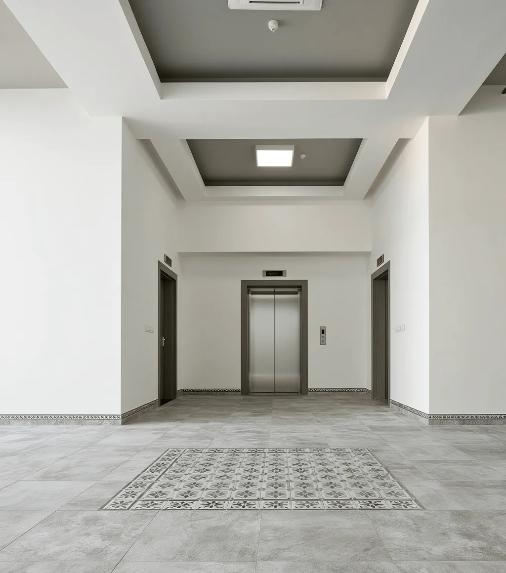 Apartment lobby with grey stone-look floor tile and a decorative patterned inlay before the lift