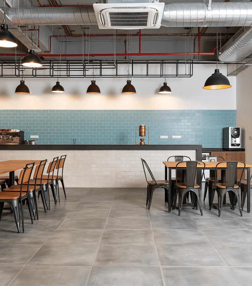 Café floored in light grey concrete-look tile, with a blue subway-tile counter backsplash