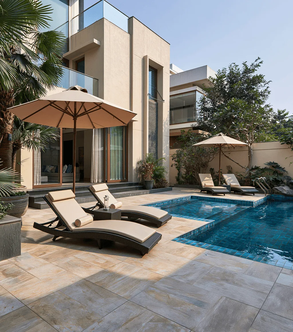 Poolside terrace in beige textured stone-look tile, with sun loungers beside a tiled swimming pool